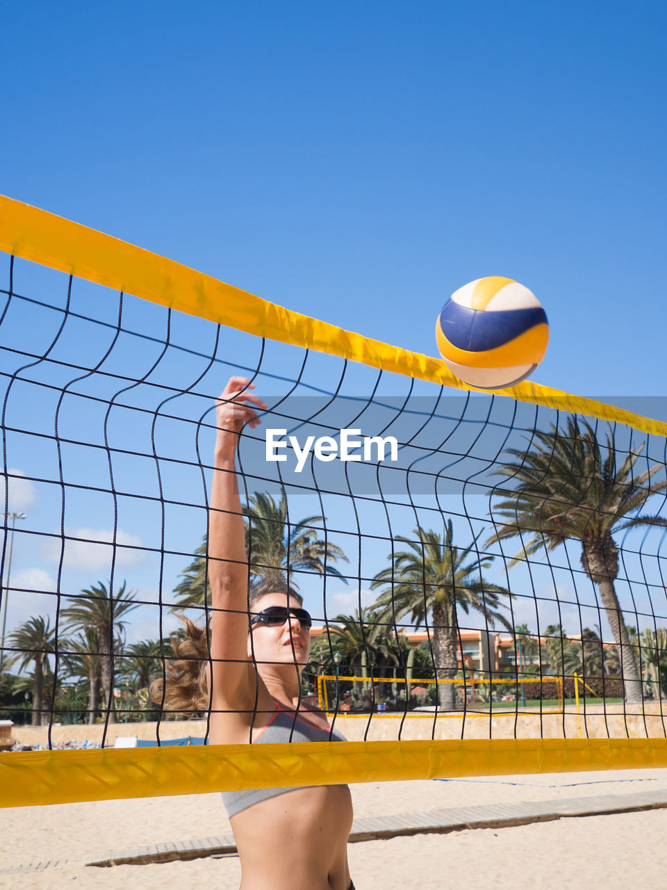 Woman playing volleyball at beach against sky