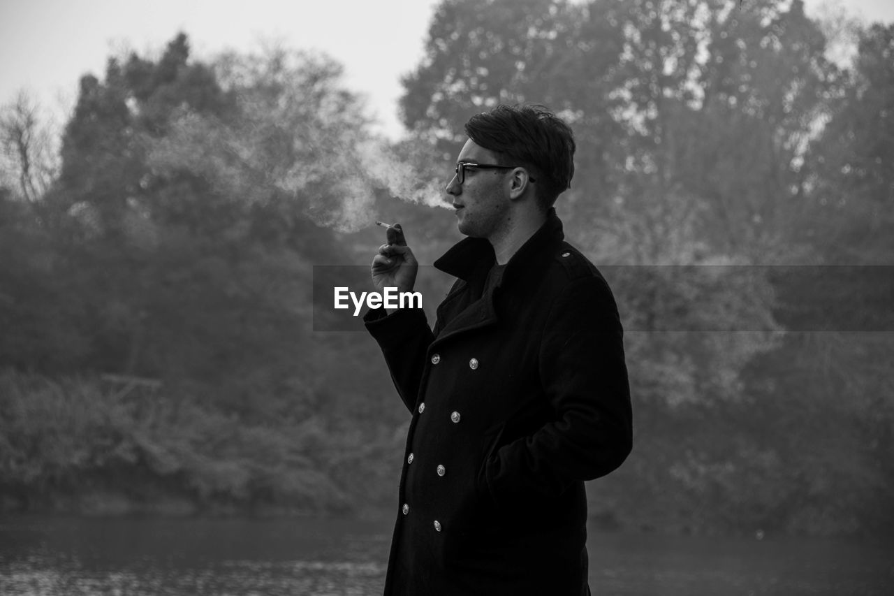 Young man smoking by lake