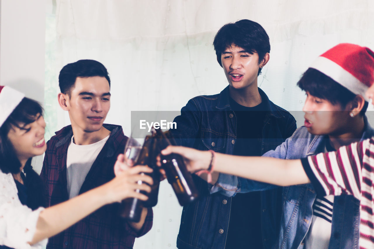 Friends toasting beer bottles during celebration at home