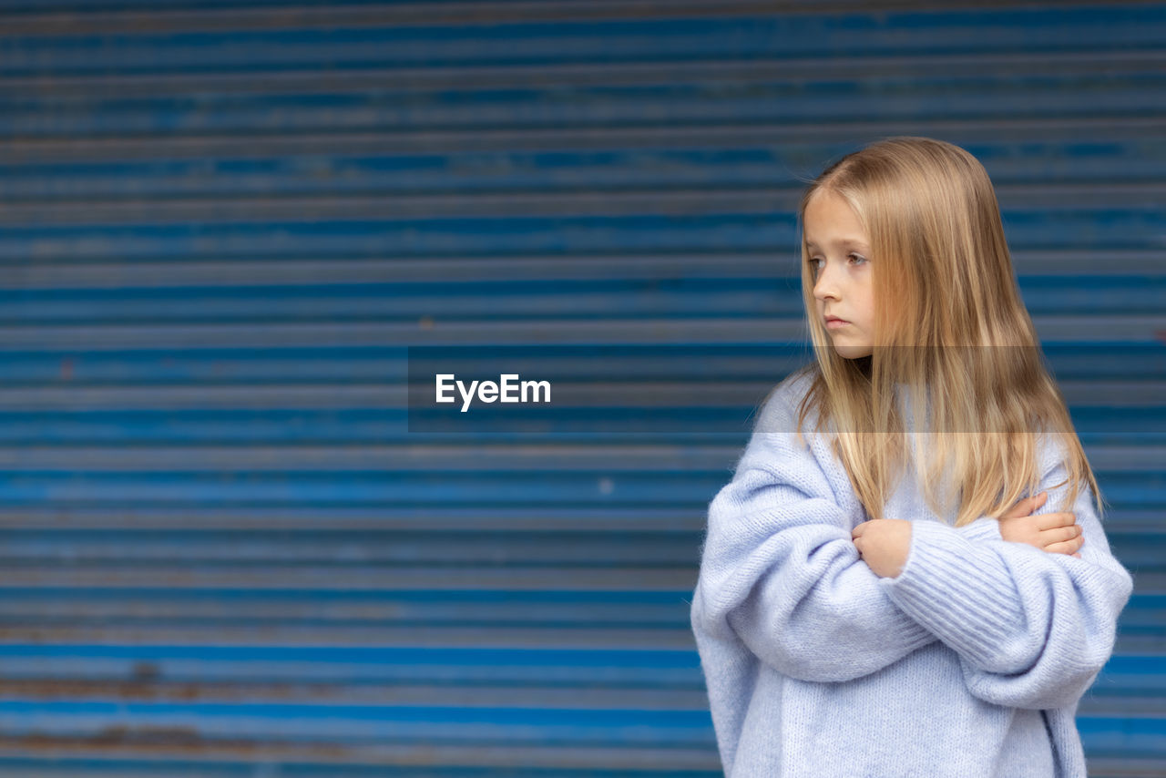 portrait of young woman standing against corrugated iron