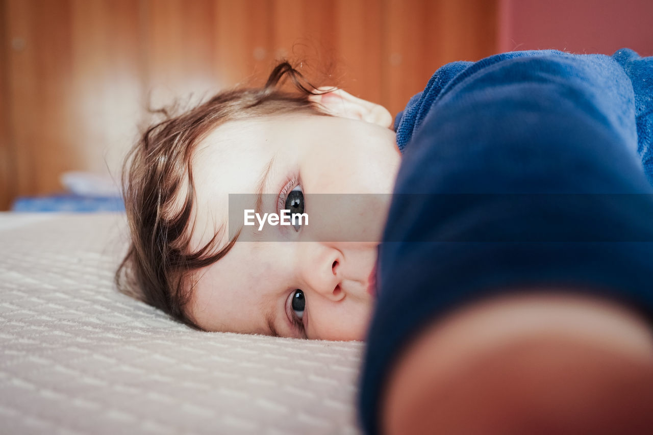 Portrait of cute baby girl on bed at home