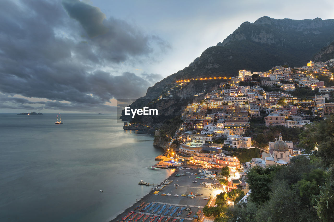 HIGH ANGLE VIEW OF SEA BY CITY AGAINST SKY