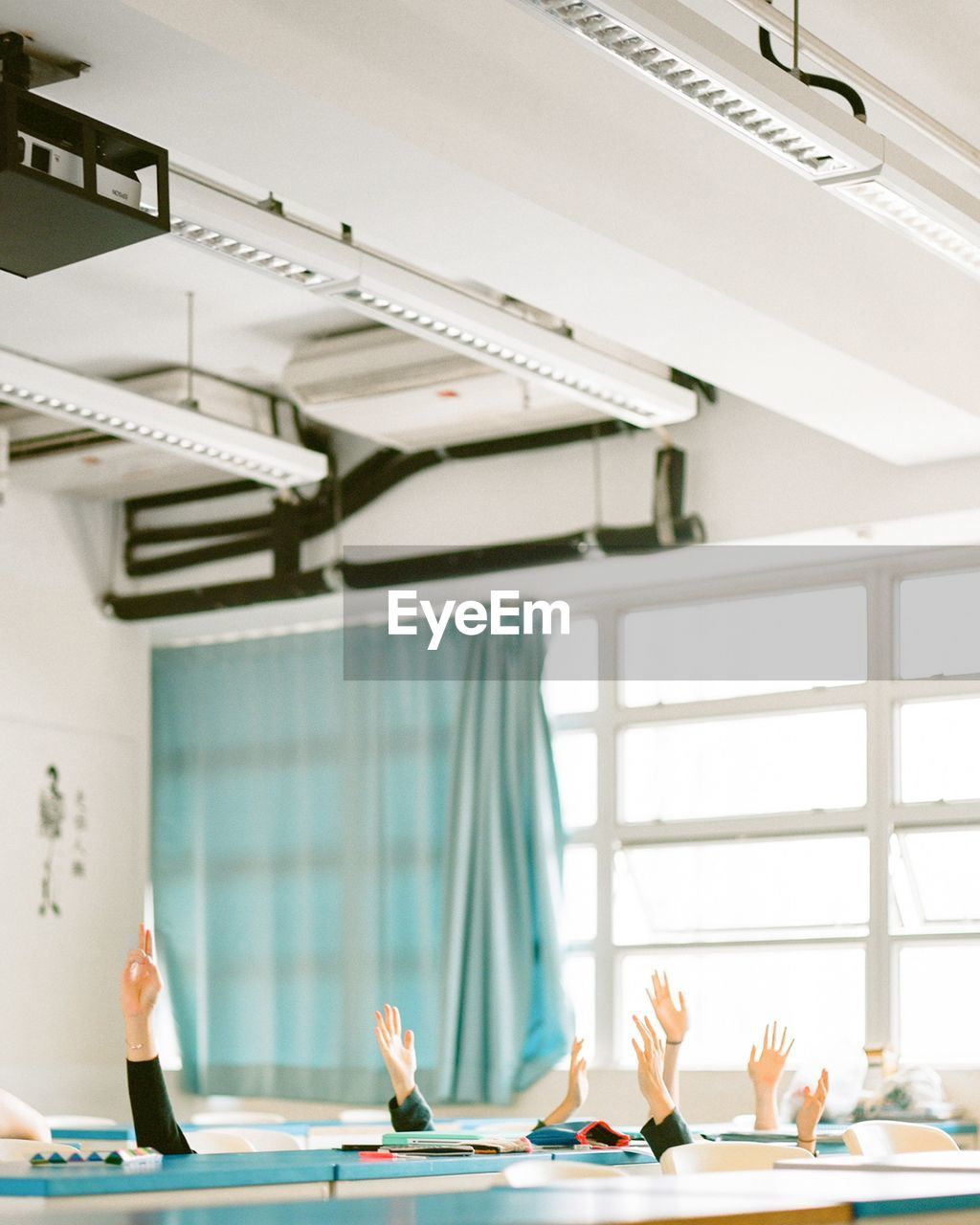 Cropped image of hands raised in classroom