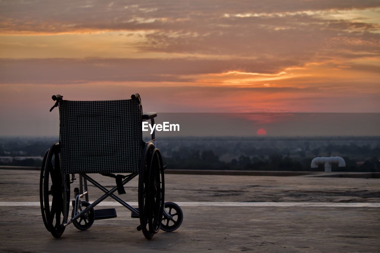 An empty wheelchair on the deck as the sun sets.