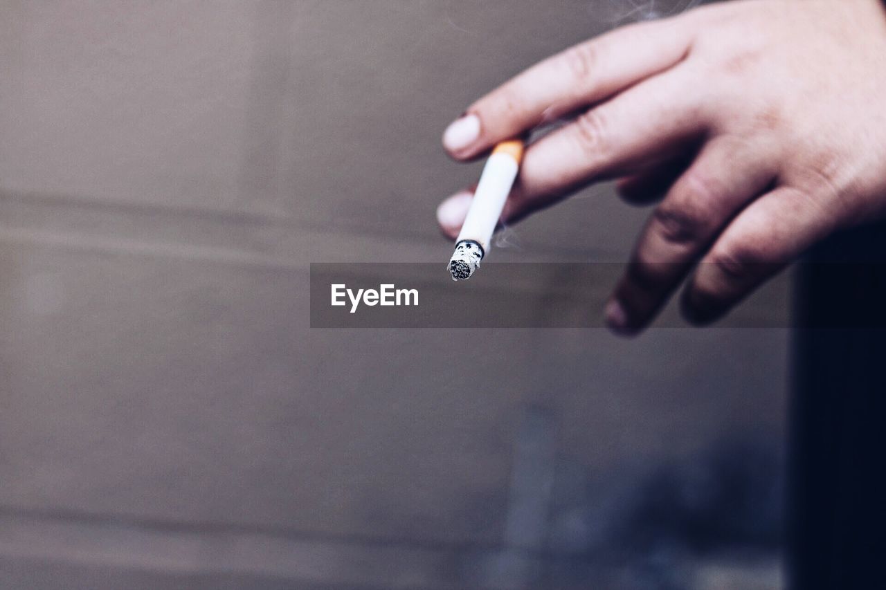 Cropped image of hand holding cigarette