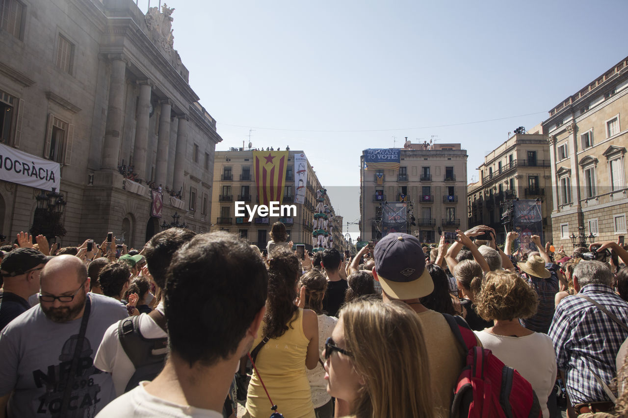 PEOPLE STANDING ON STREET AGAINST CLEAR SKY