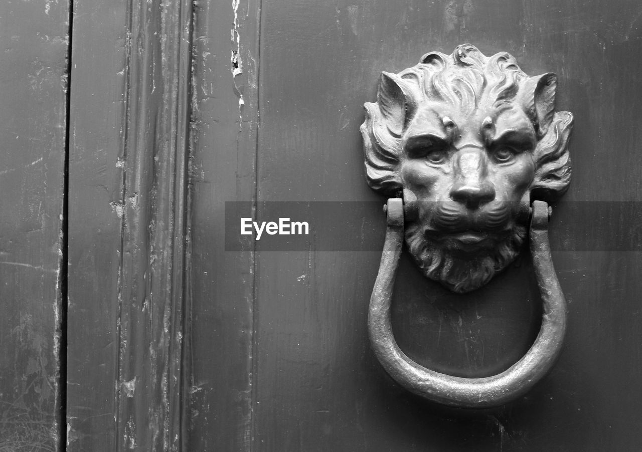 CLOSE-UP OF DOOR KNOCKER ON ROCK WITH CLOSED DOORS