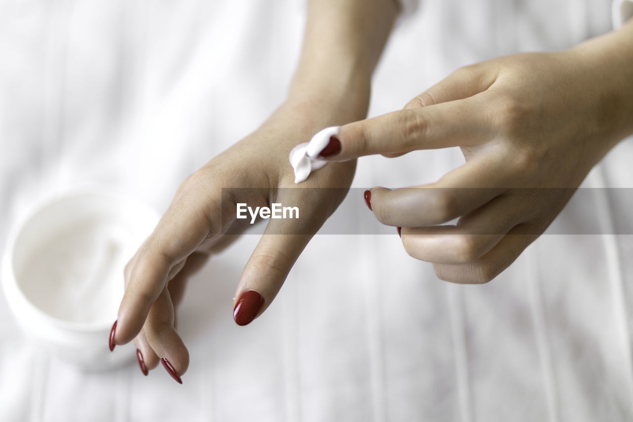 Beautiful groomed woman's hands with cream jar on the blanket. moisturizing cream for soft skin