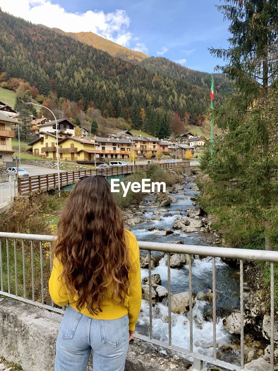 Rear view of woman standing by railing against mountain