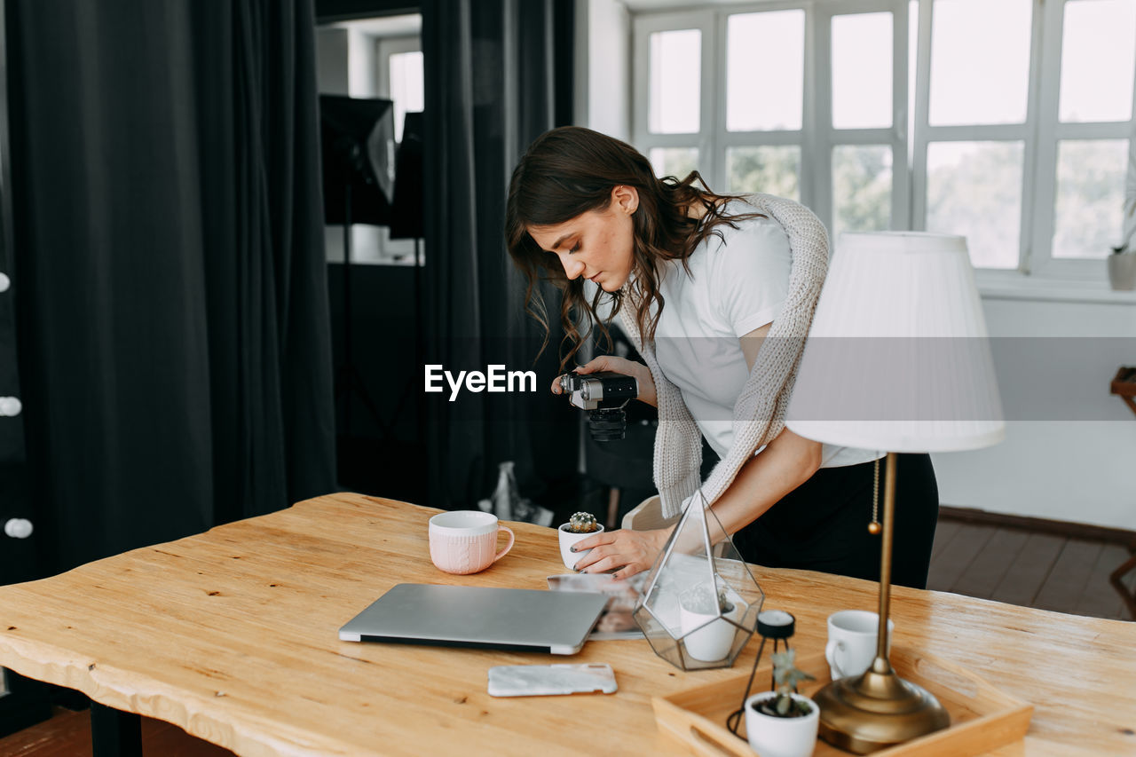 Woman photographer freelancer shoots content for business at home office