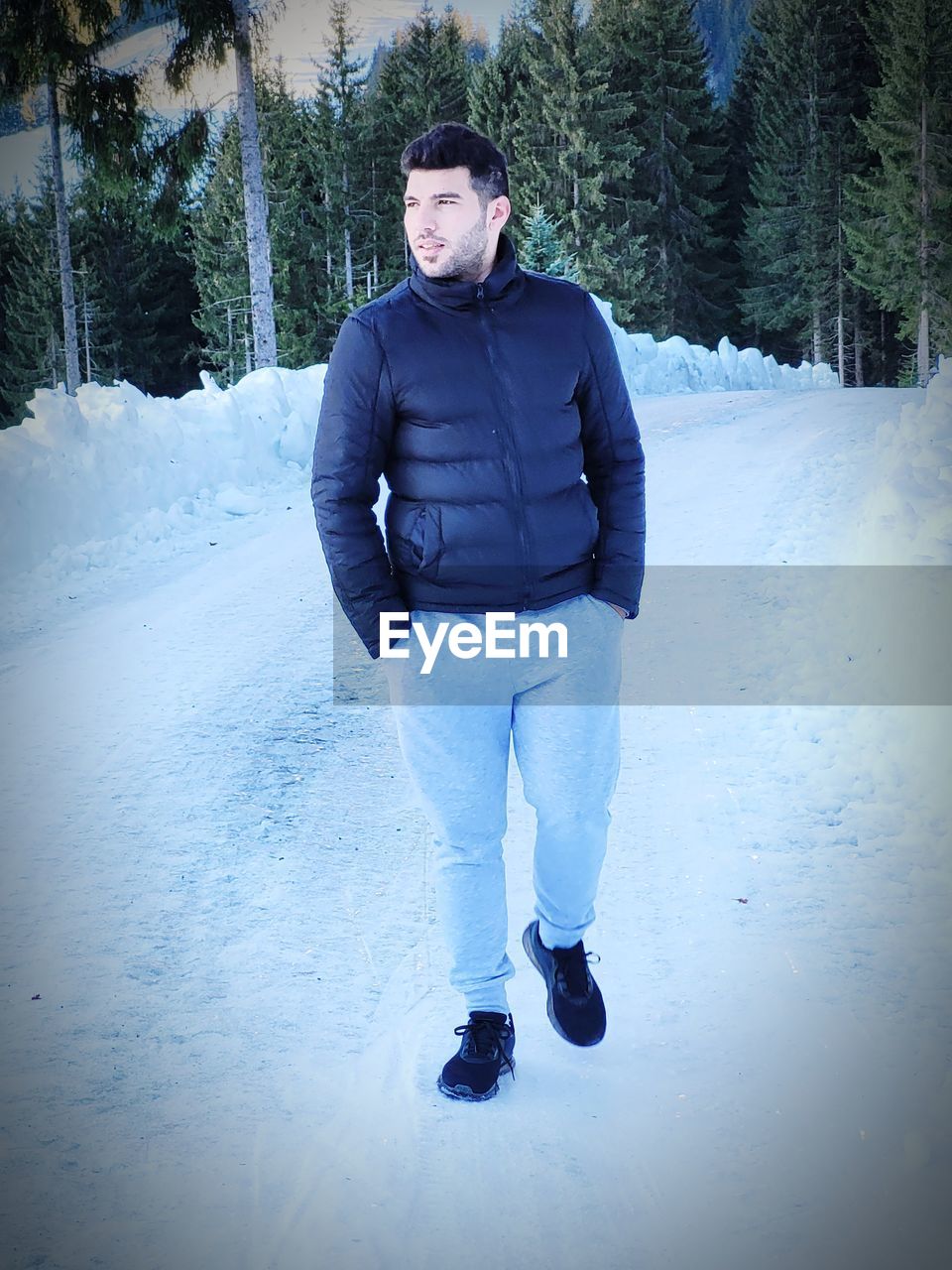 winter, cold temperature, snow, one person, footwear, clothing, tree, nature, warm clothing, blue, full length, leisure activity, young adult, adult, sports, front view, plant, lifestyles, day, portrait, men, standing, winter sports, land, forest, frozen, ice, outdoors, holiday, environment, looking at camera, hat, person, freezing, vacation