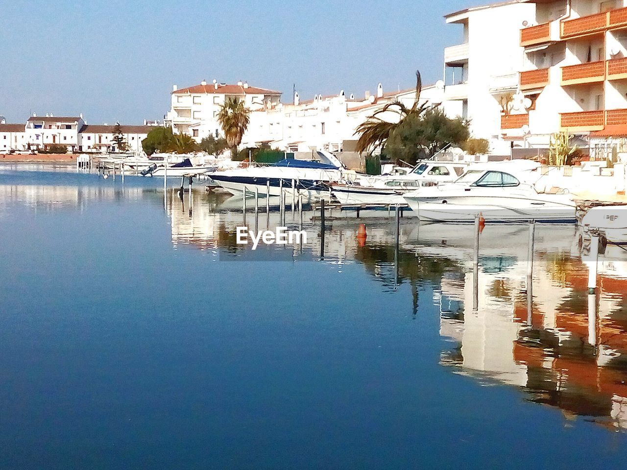 SAILBOATS MOORED IN LAKE AGAINST CLEAR SKY