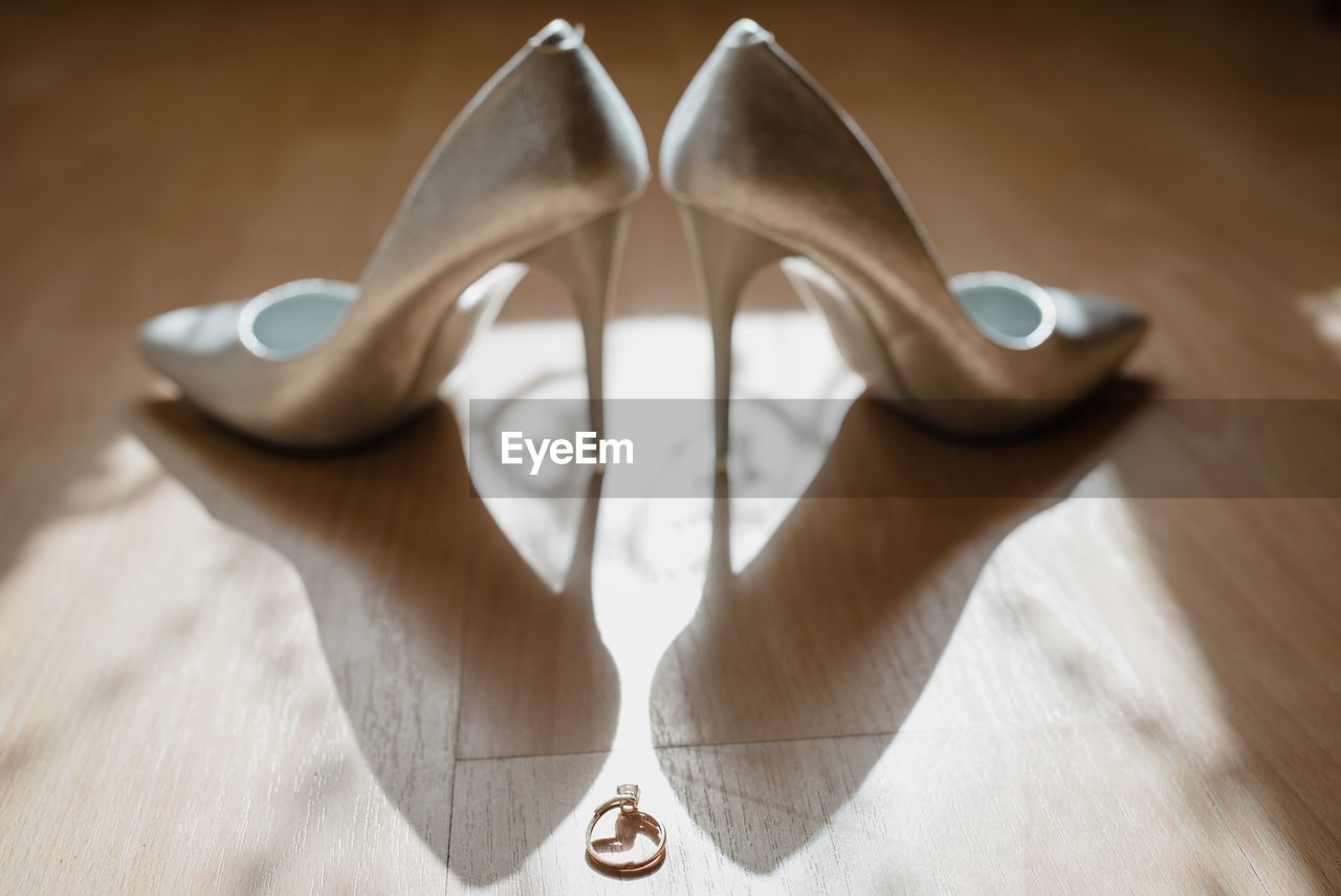 Close-up of high heels and ring on hardwood floor
