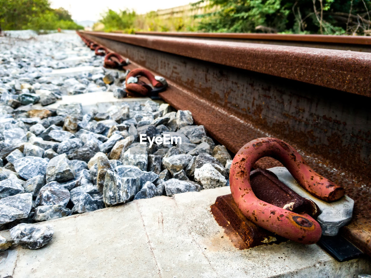 CLOSE-UP OF RUSTY METAL CHAIN ON RAILROAD TRACK