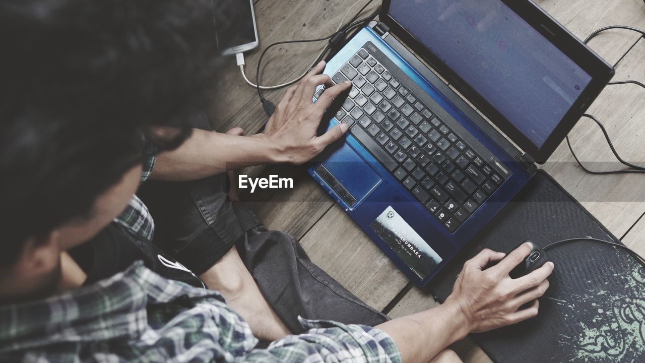 HIGH ANGLE VIEW OF MAN WORKING WITH LAPTOP