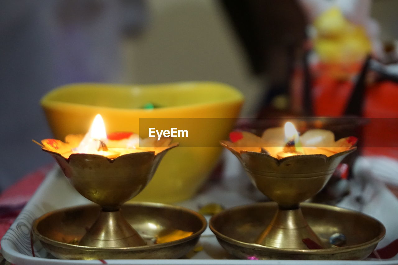 Close-up of illuminated diyas in tray at home