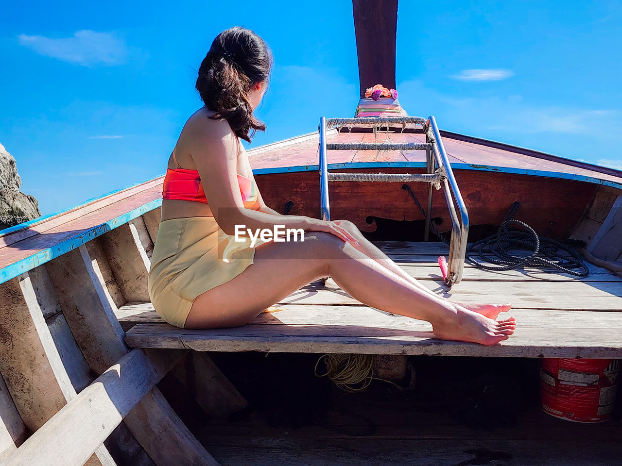 one person, adult, full length, sitting, women, relaxation, nature, young adult, sky, leisure activity, vacation, trip, summer, water, holiday, sunlight, lifestyles, wood, day, clothing, transportation, nautical vessel, casual clothing, travel, boat, hairstyle, outdoors, side view, blue, mode of transportation, human leg, person, barefoot, vehicle, female, sea, fashion