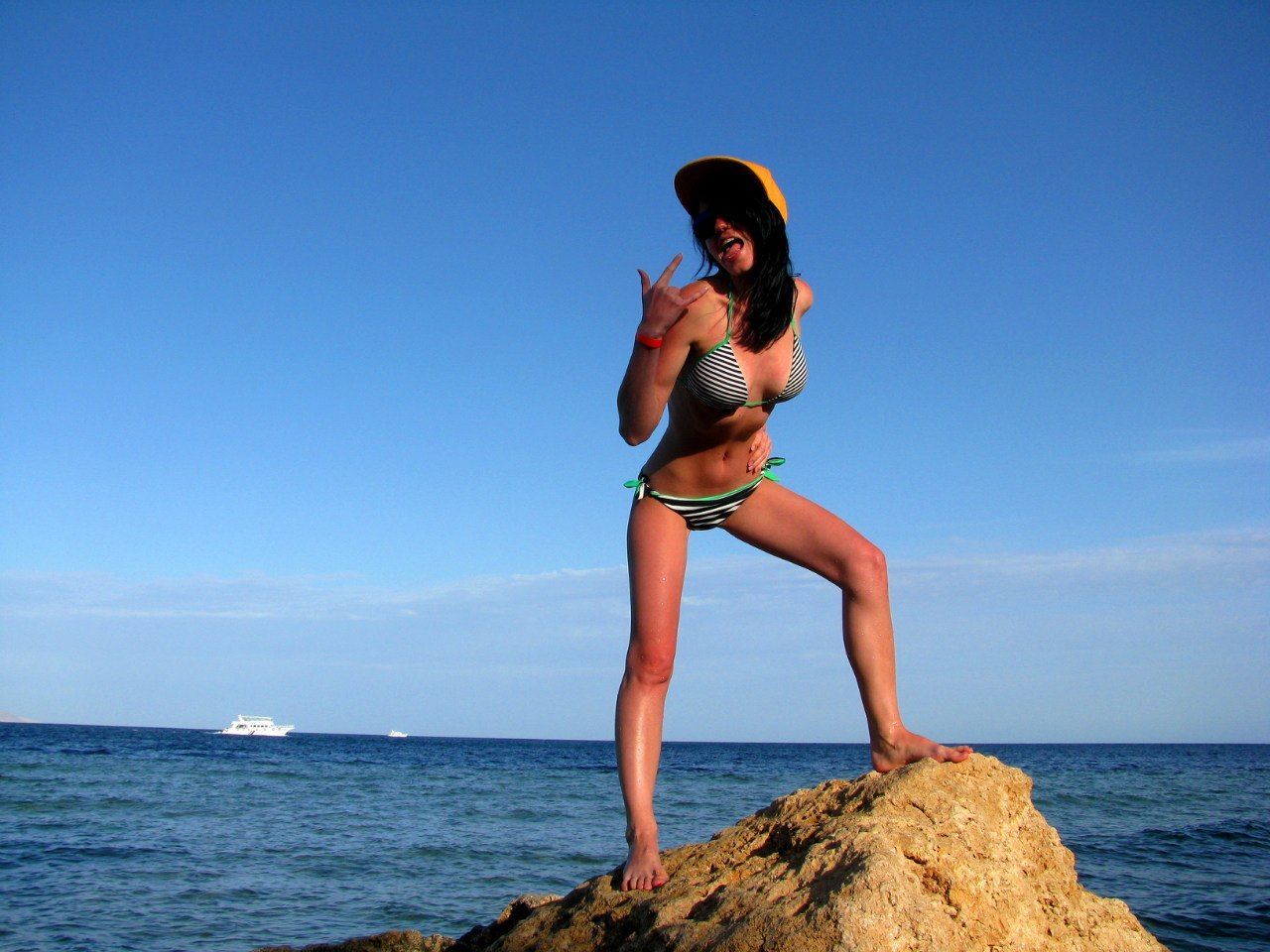 Low angle view of model posing on rock by sea against sky