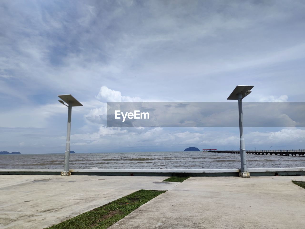 sky, cloud, sea, water, nature, coast, walkway, street light, wind, ocean, shore, beach, no people, beauty in nature, day, street, environment, road, tranquility, scenics - nature, outdoors, renewable energy, land, tranquil scene, horizon, architecture, alternative energy, environmental conservation, lighting equipment, sign, blue, transportation, guidance, road sign