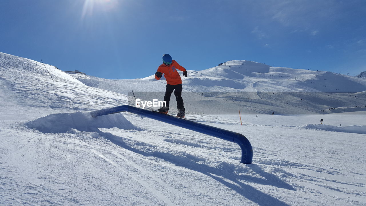 MAN SKIING ON SNOWCAPPED MOUNTAINS AGAINST SKY