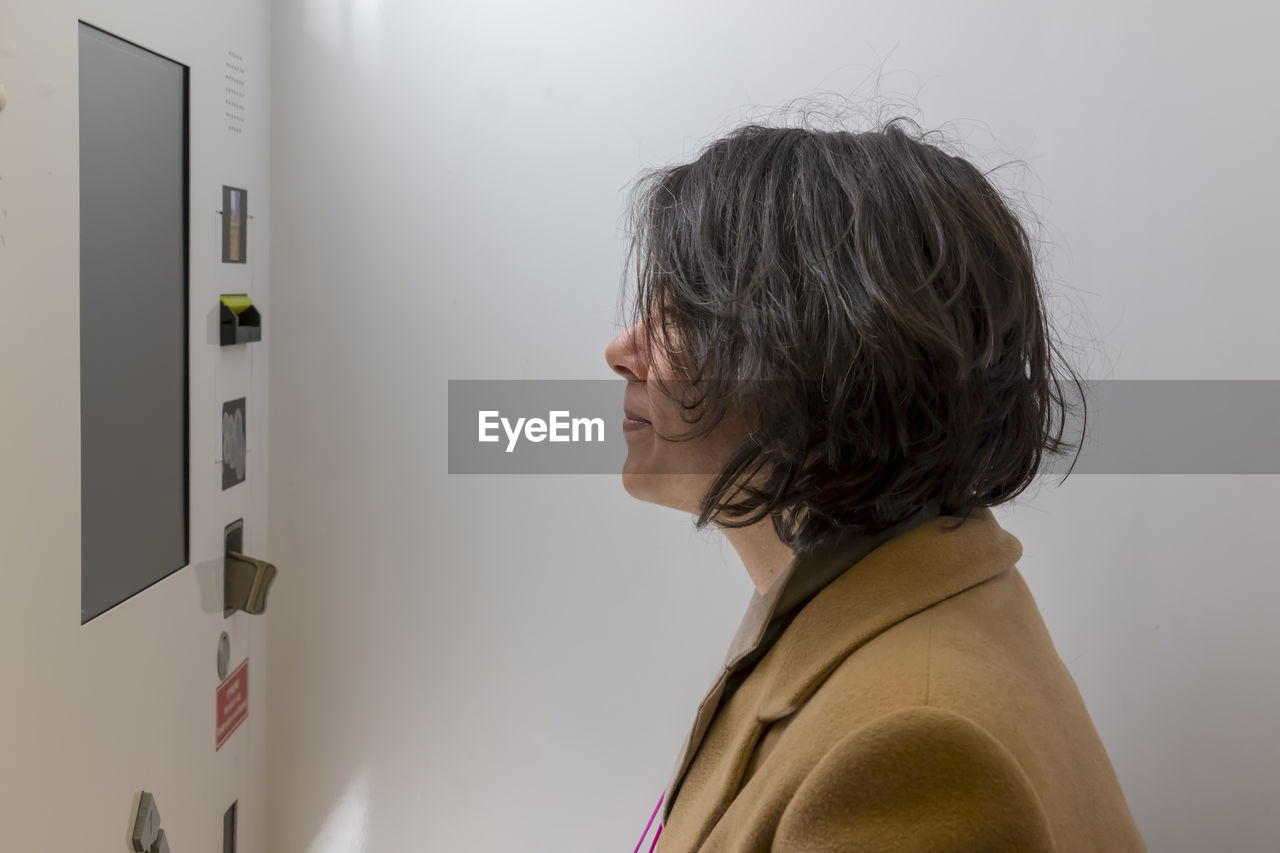 Side view of woman standing by machinery in wall