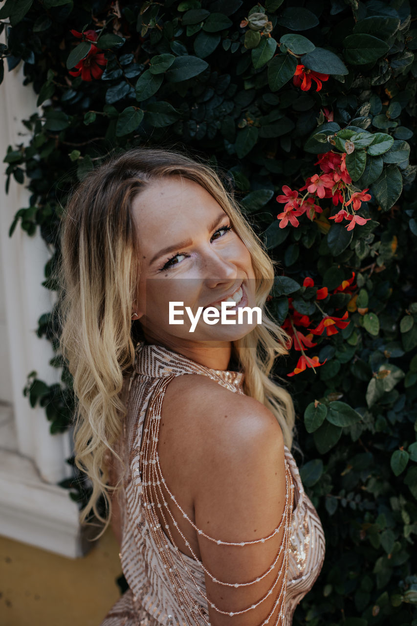 Portrait of smiling young woman standing against plants