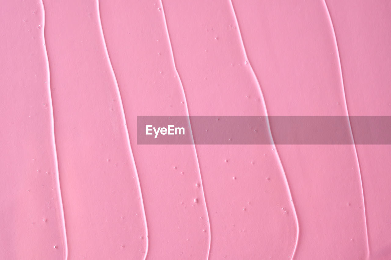 The texture of the cosmetic gel on a pink background.