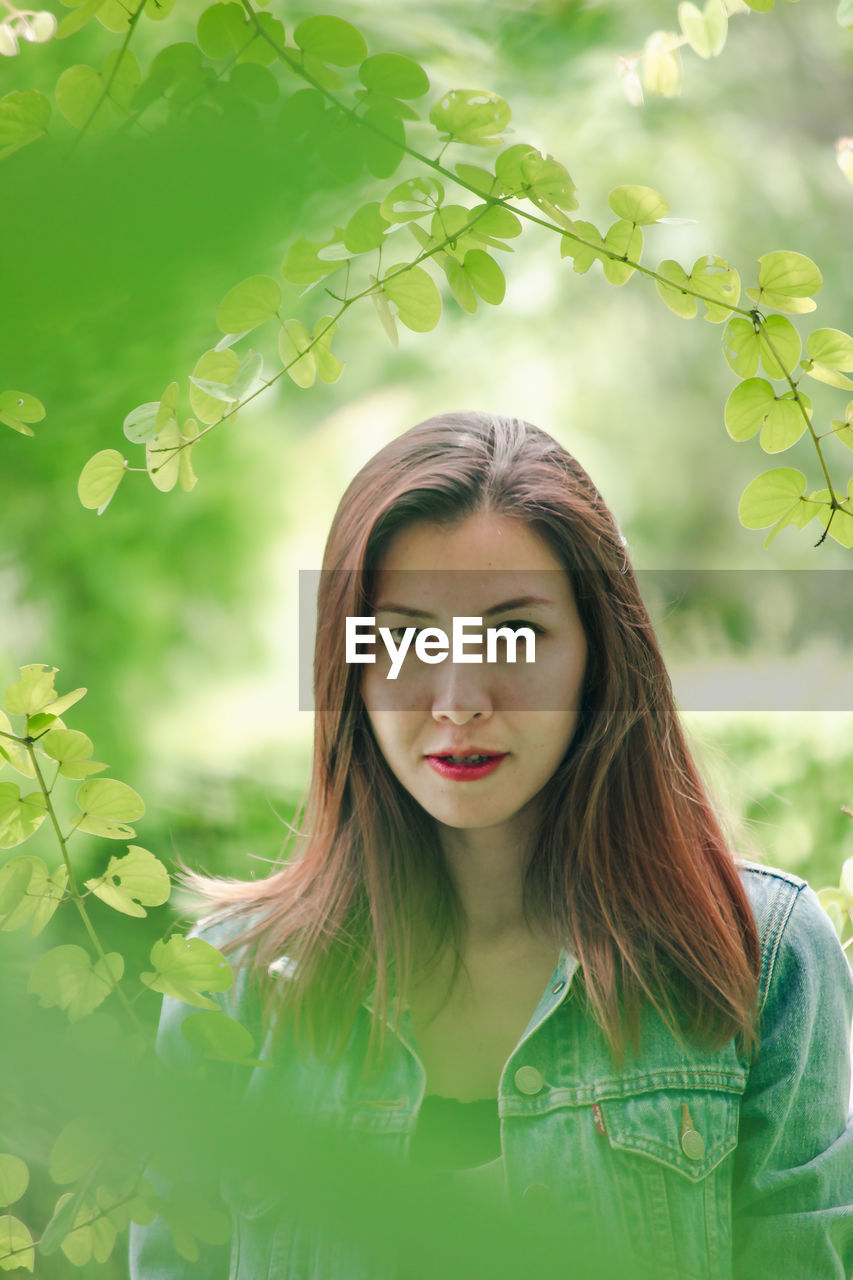 Portrait of beautiful woman standing by plant