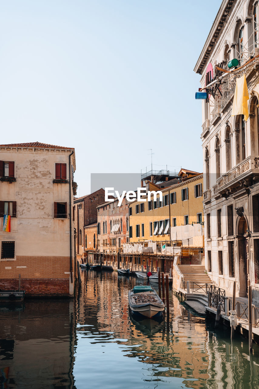 Small wooden boat filled with construction rubbish moored on a narrow canal in venice, italy.