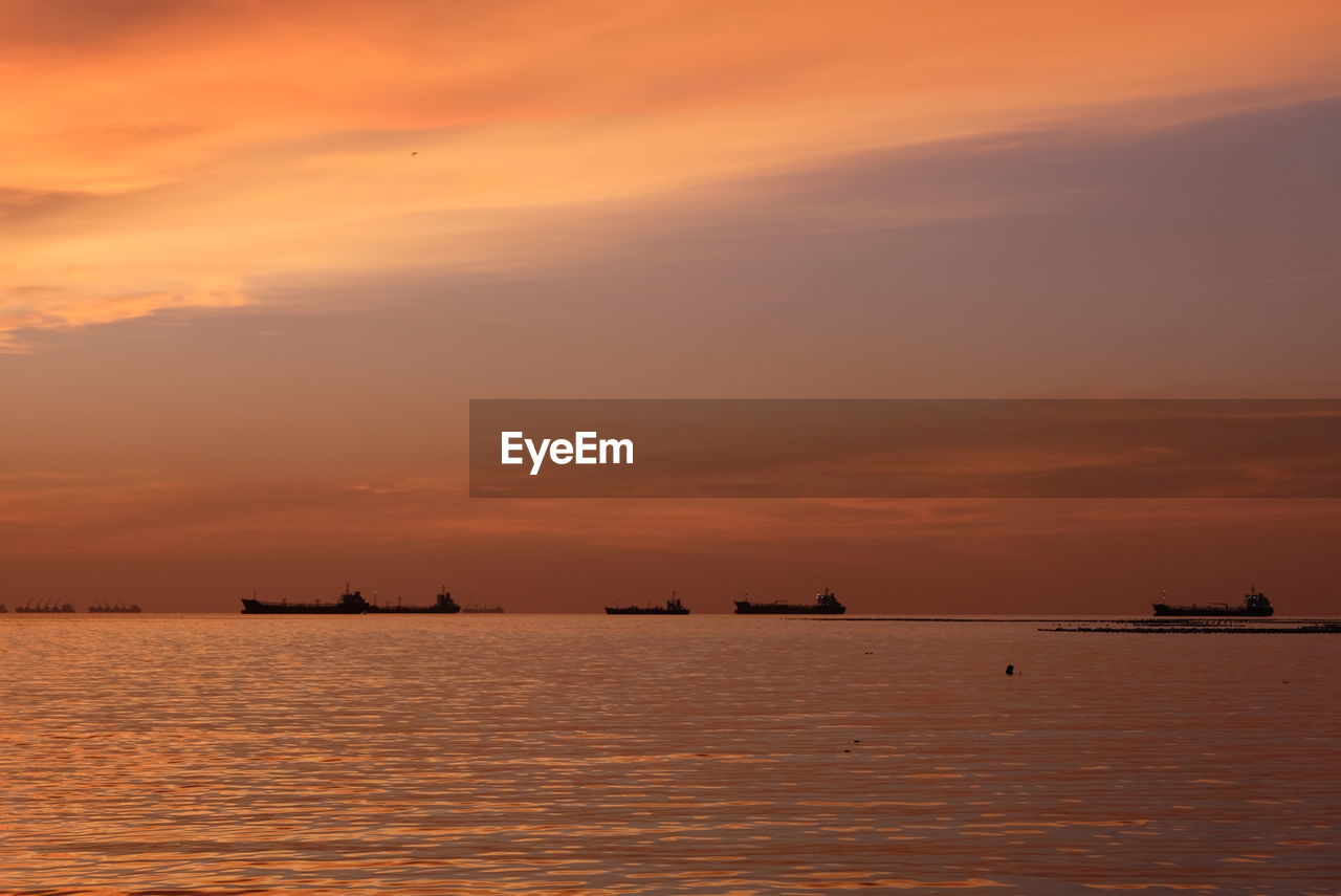 SILHOUETTE BOATS IN SEA AGAINST ORANGE SKY