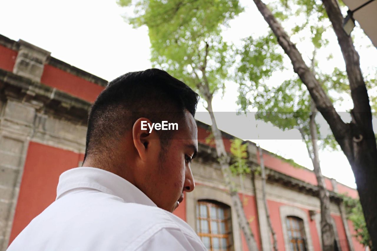 Close-up of young man standing against building