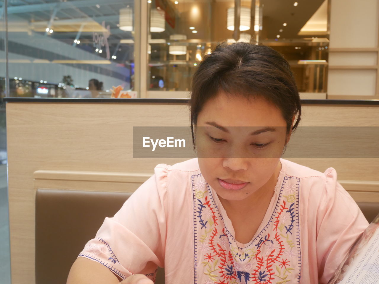 Mid adult woman reading menu in restaurant