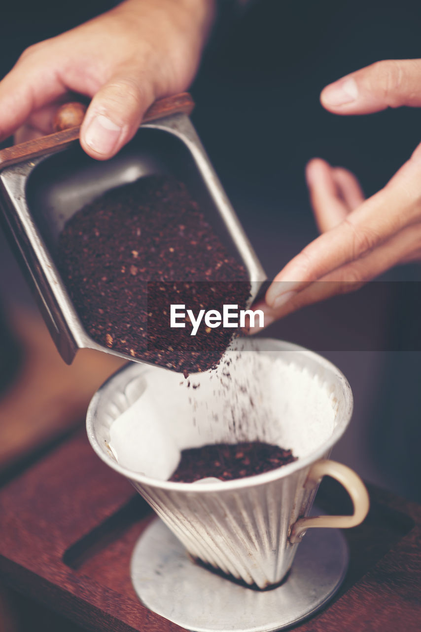 Cropped hand pouring coffee powder in coffee cup