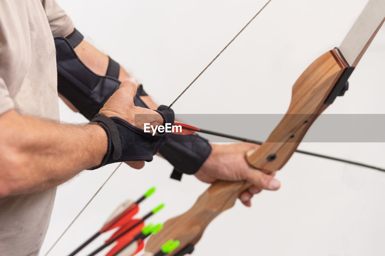 Midsection of man aiming with arrow against clear sky