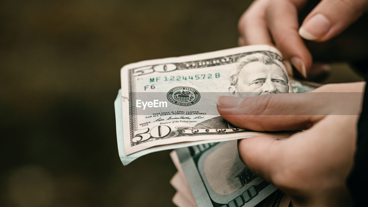 cropped hand of woman holding paper currency