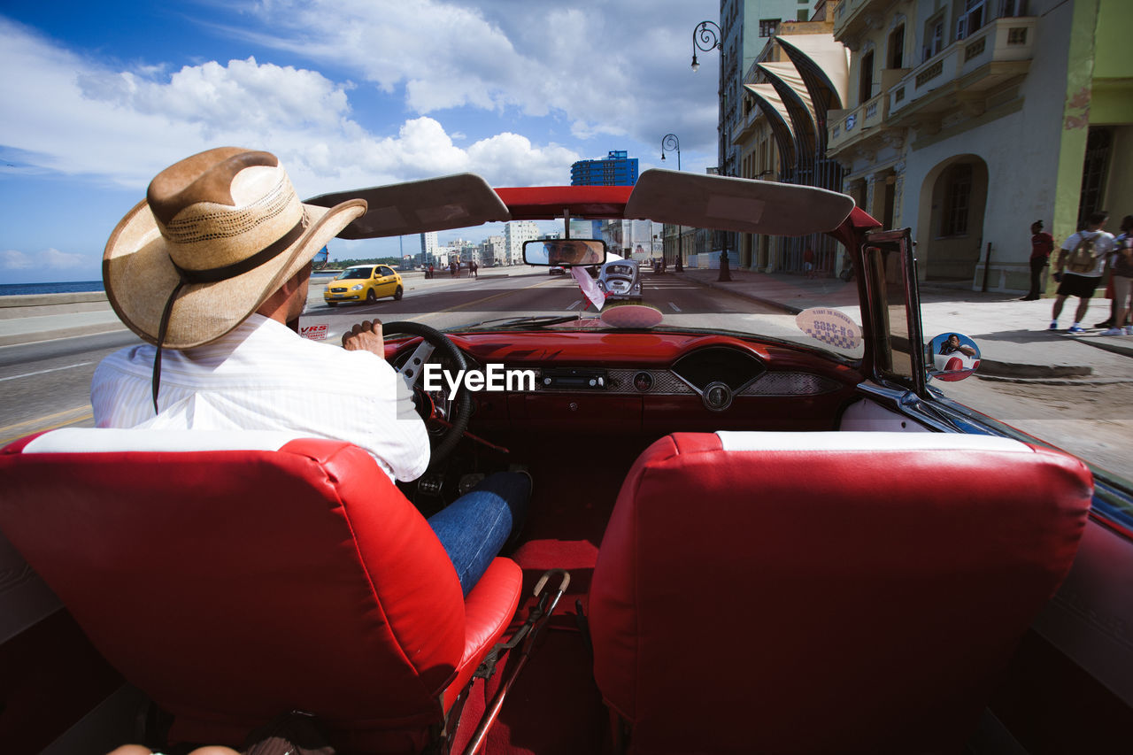 REAR VIEW OF MAN TRAVELING IN BUS