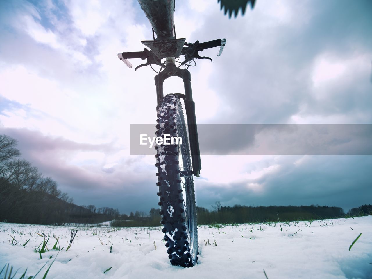 Bicycle wheel in the snow. detailed extreme close up low angle view. snowy filed in open landscape.