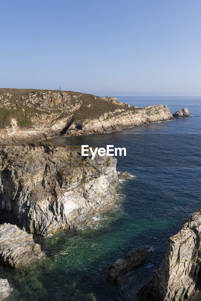 water, sea, cliff, sky, land, scenics - nature, rock, beauty in nature, coast, nature, terrain, ocean, clear sky, beach, shore, no people, tranquility, blue, tranquil scene, horizon, environment, day, travel destinations, non-urban scene, coastline, horizon over water, travel, landscape, outdoors, rock formation, bay, cove, body of water, sunny, tourism, idyllic, sunlight