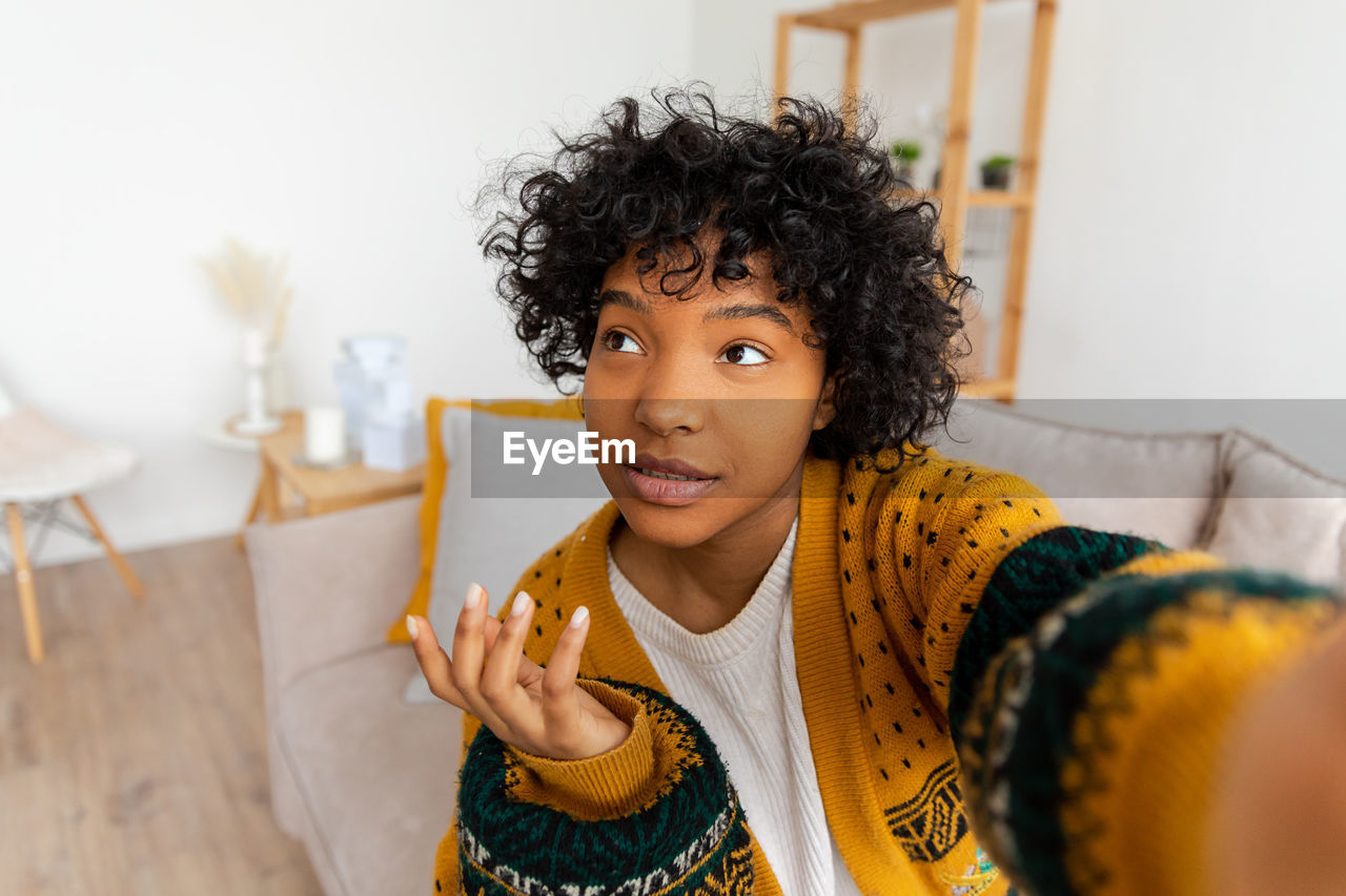 portrait of smiling young woman sitting on floor at home