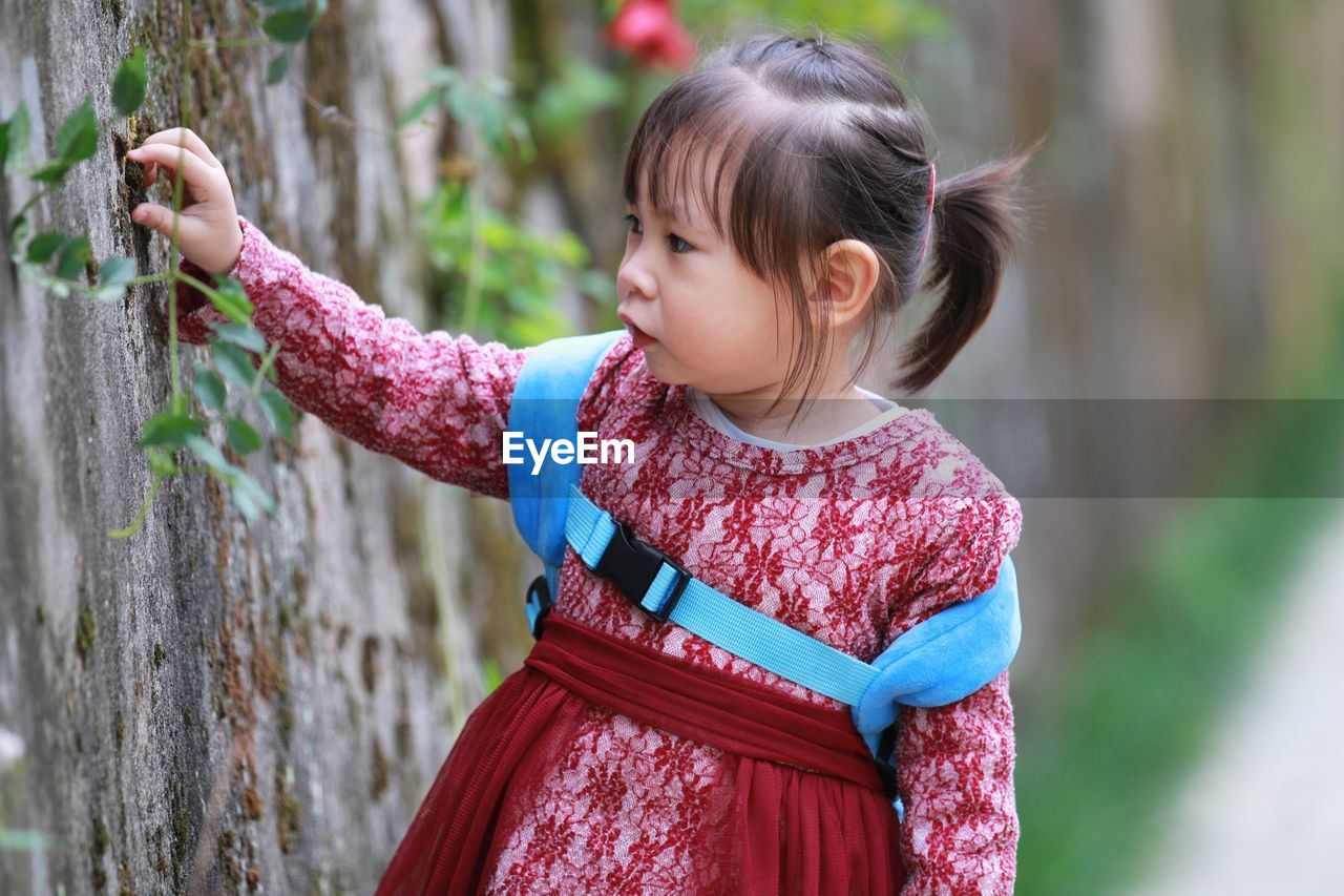 Cute girl standing by weathered wall