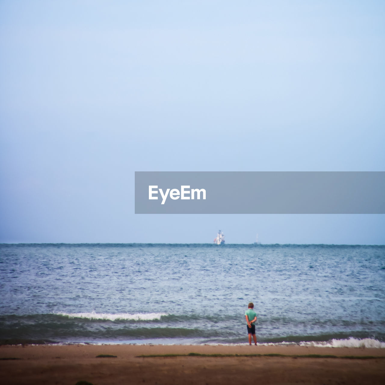 Boy at beach by sea against clear sky