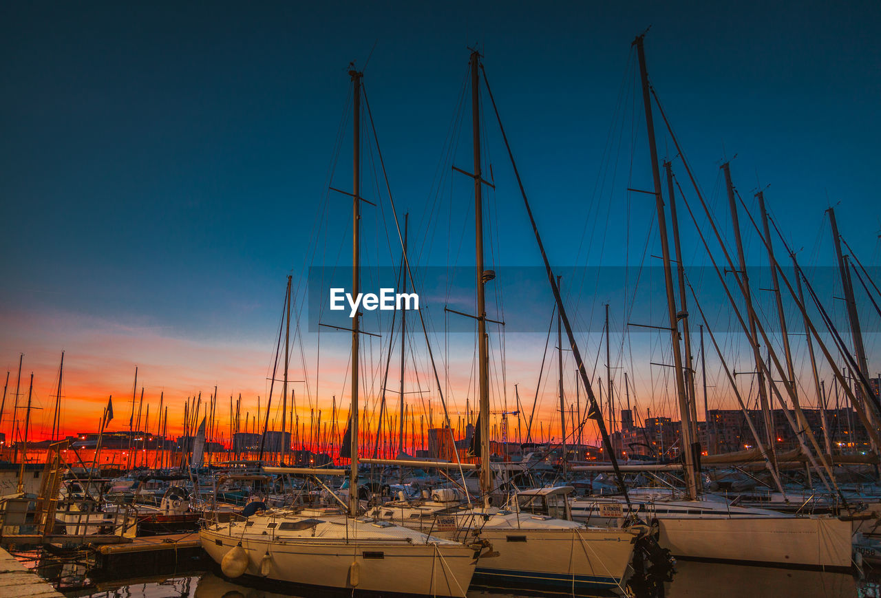 BOATS MOORED AT HARBOR AGAINST SKY