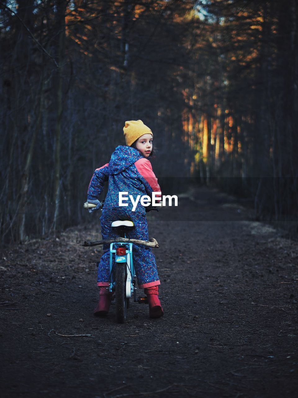 Girl on bike in dark evening park at spring