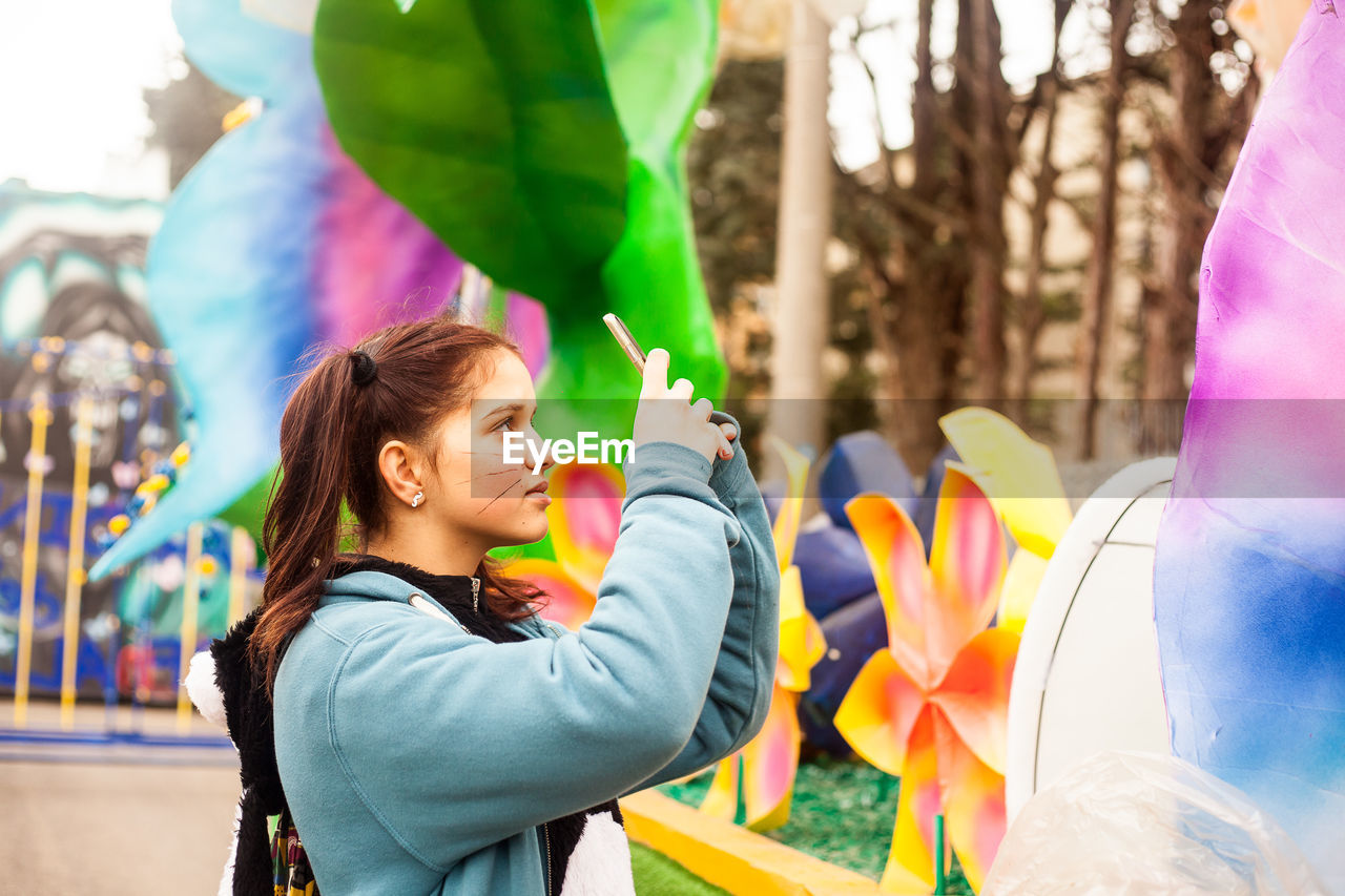 Teenage girl photographing at traveling carnival