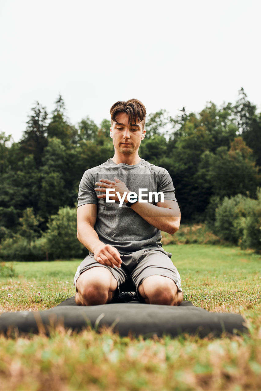 Young man doing exercises outside on grass during his calisthenics workout