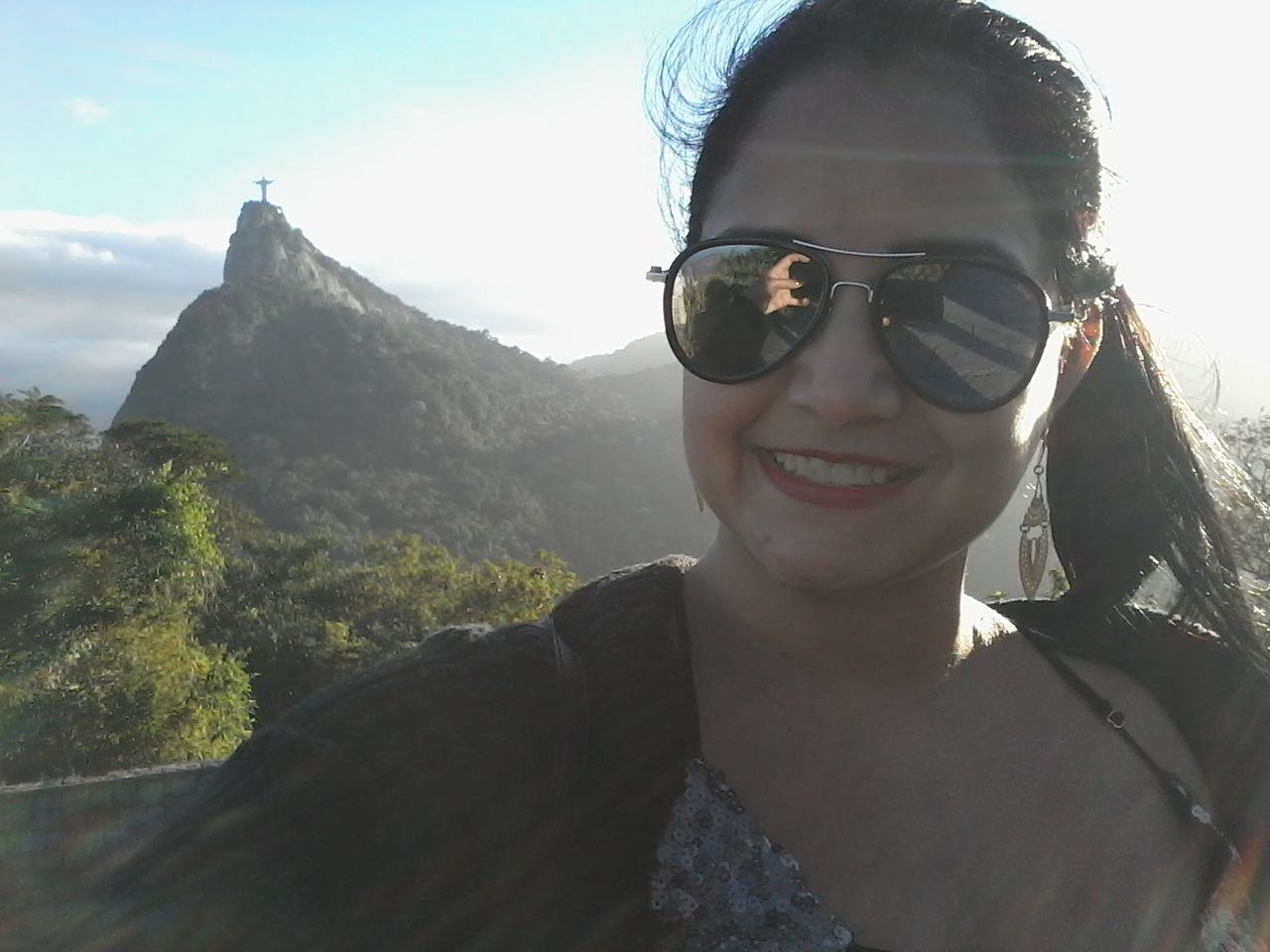 Close-up of smiling woman wearing sunglasses against mountain peak