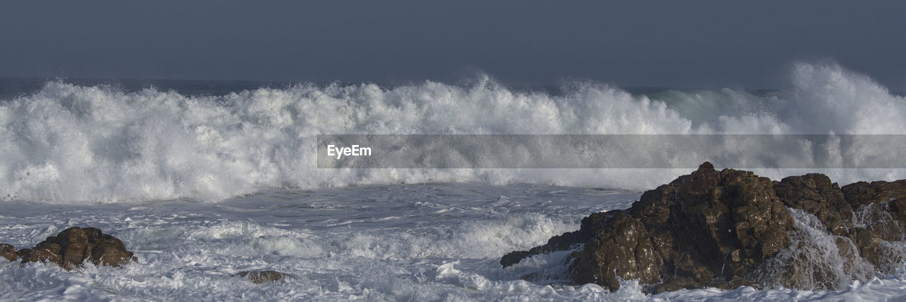 PANORAMIC VIEW OF SEA WAVES SPLASHING ON ROCKS