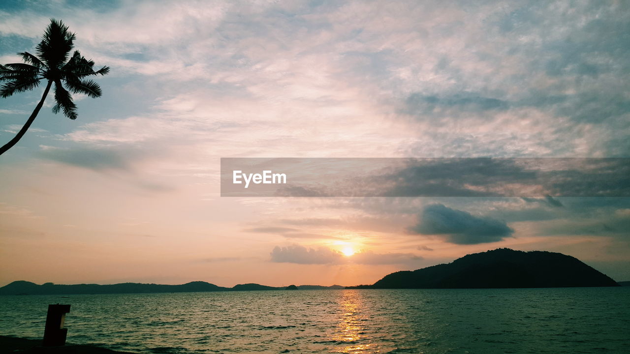 Scenic view of sea against cloudy sky during sunrise