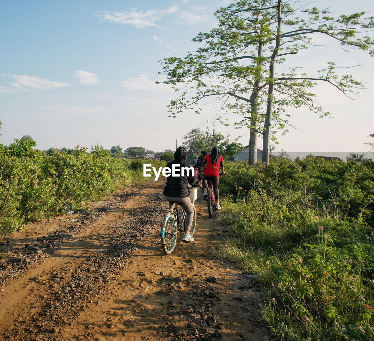 Girl riding bicycle on road against sky