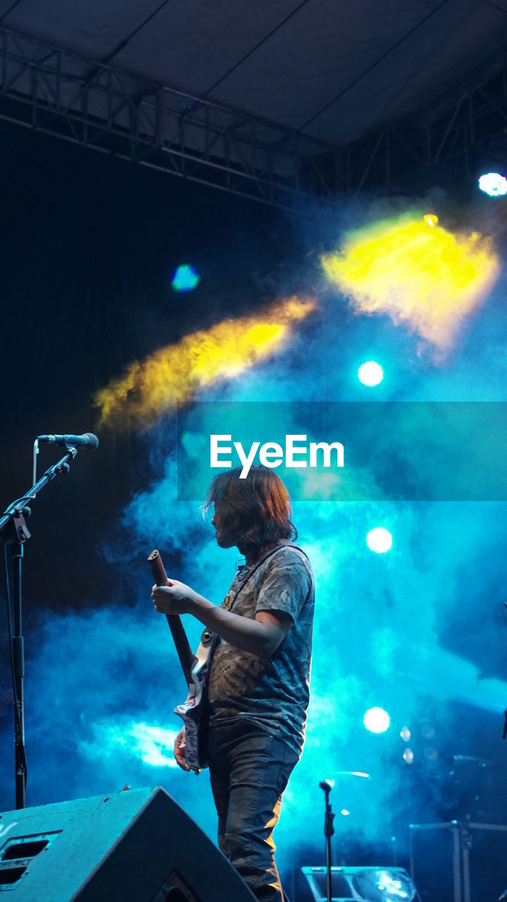 Side view of musician playing guitar during music festival